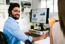 Firozabad-smiling-indian-man-working-as-customer-support-operator-headset-call-center-portrait-sales-agent-sitting-desk